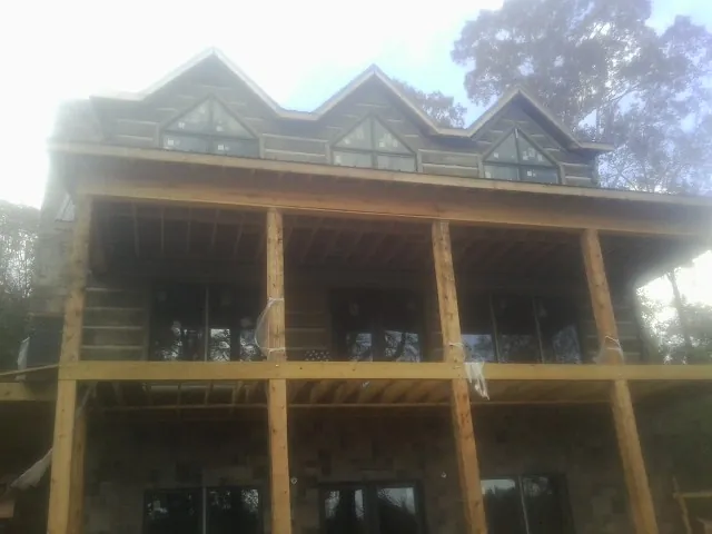 Dormers and porch framing on a large log home under construction — Roof Coating work by our crew in Oakpark