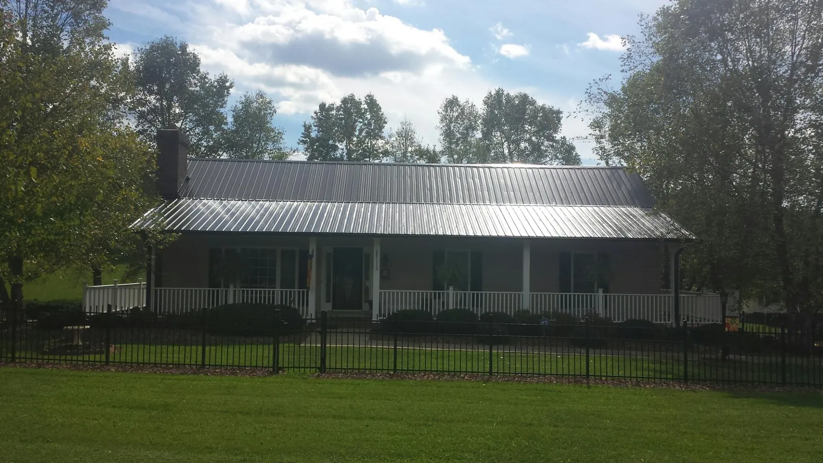 Gray metal roof on a brick ranch with a full width front porch — Gutter Guard Installation work by our crew in Oakpark
