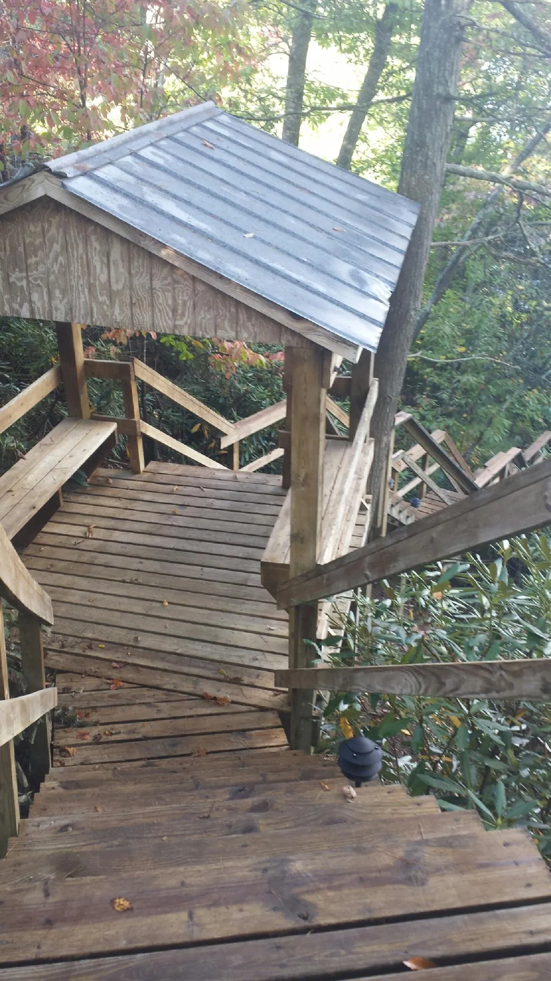 Metal roofed shelter over wooden steps on a wooded walkway — Skylight Repair & Installation work by our crew in Oakpark